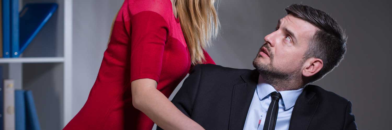 A woman in a red dress suggestively leans into a man at work creating a potentially hazardous sexual harassment scenario.
