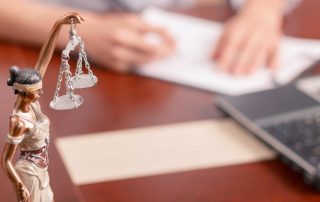Justice statue on a table with a lawyer signing papers