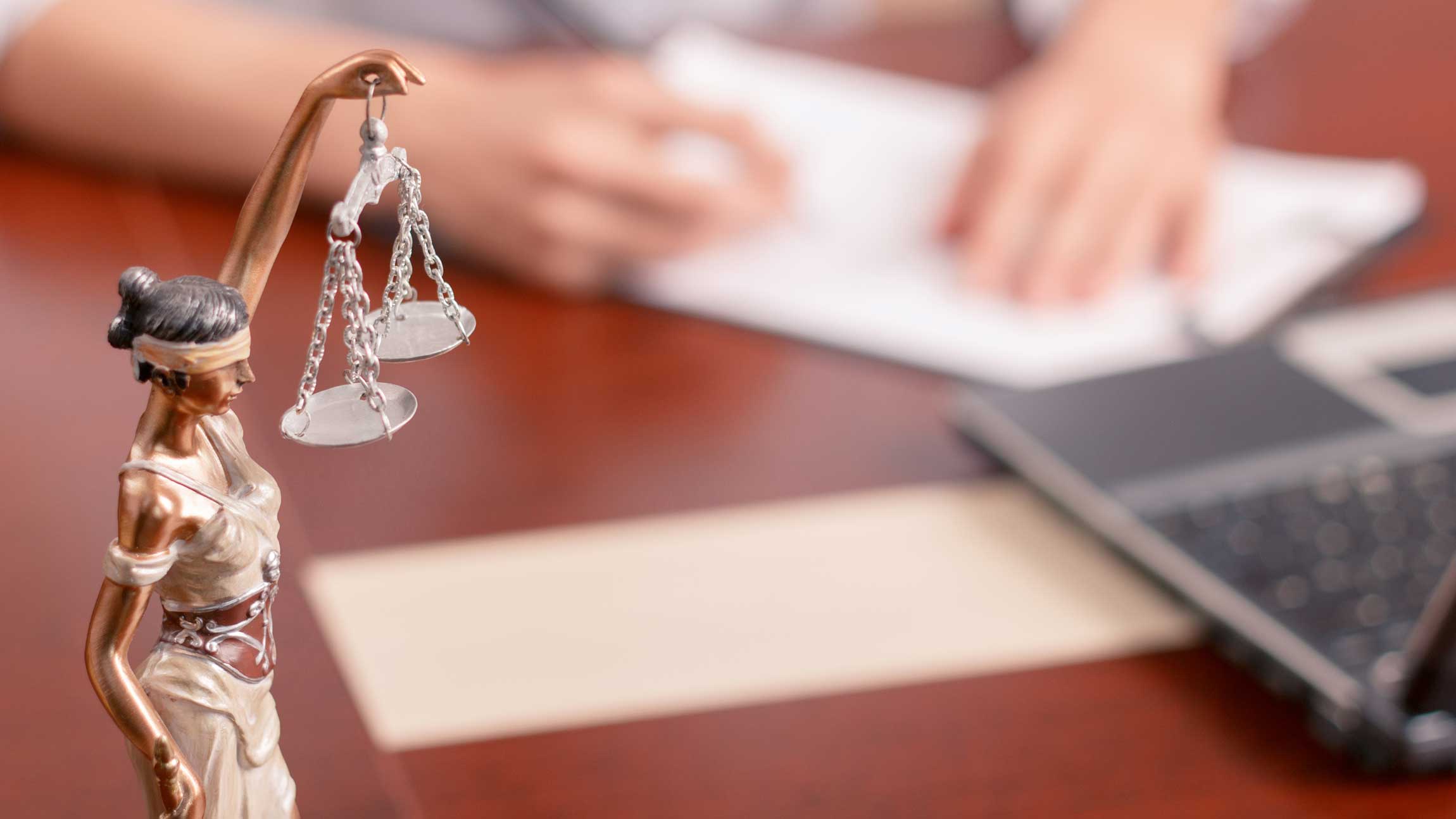 Justice statue on a table with a lawyer signing papers