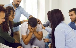 Man surround by friends crying over the loss of a loved one