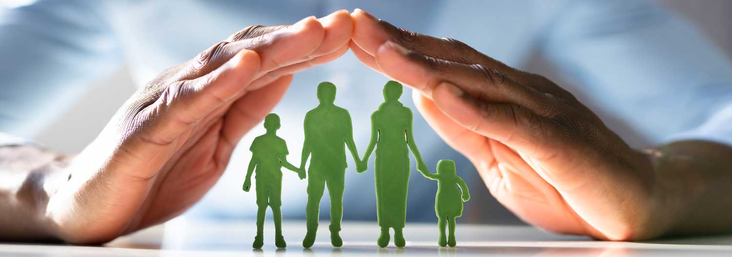 Man holding his hands like a roof over paper cut out of a family of four