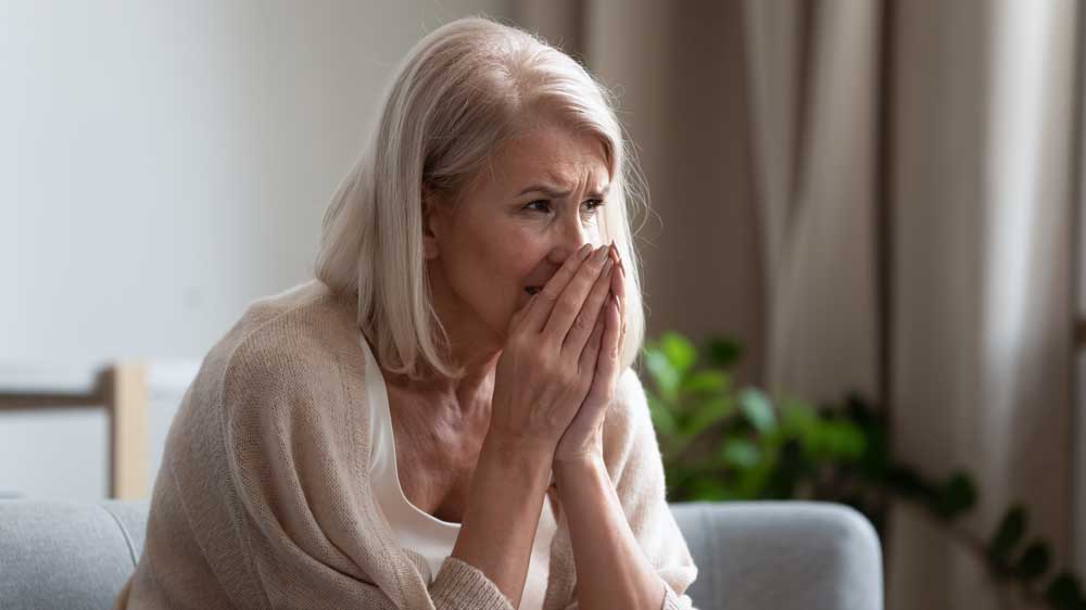 Woman distraught over loss with hands in her face