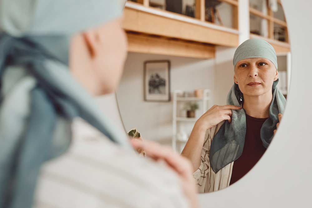 Woman with cancer looking into a mirror