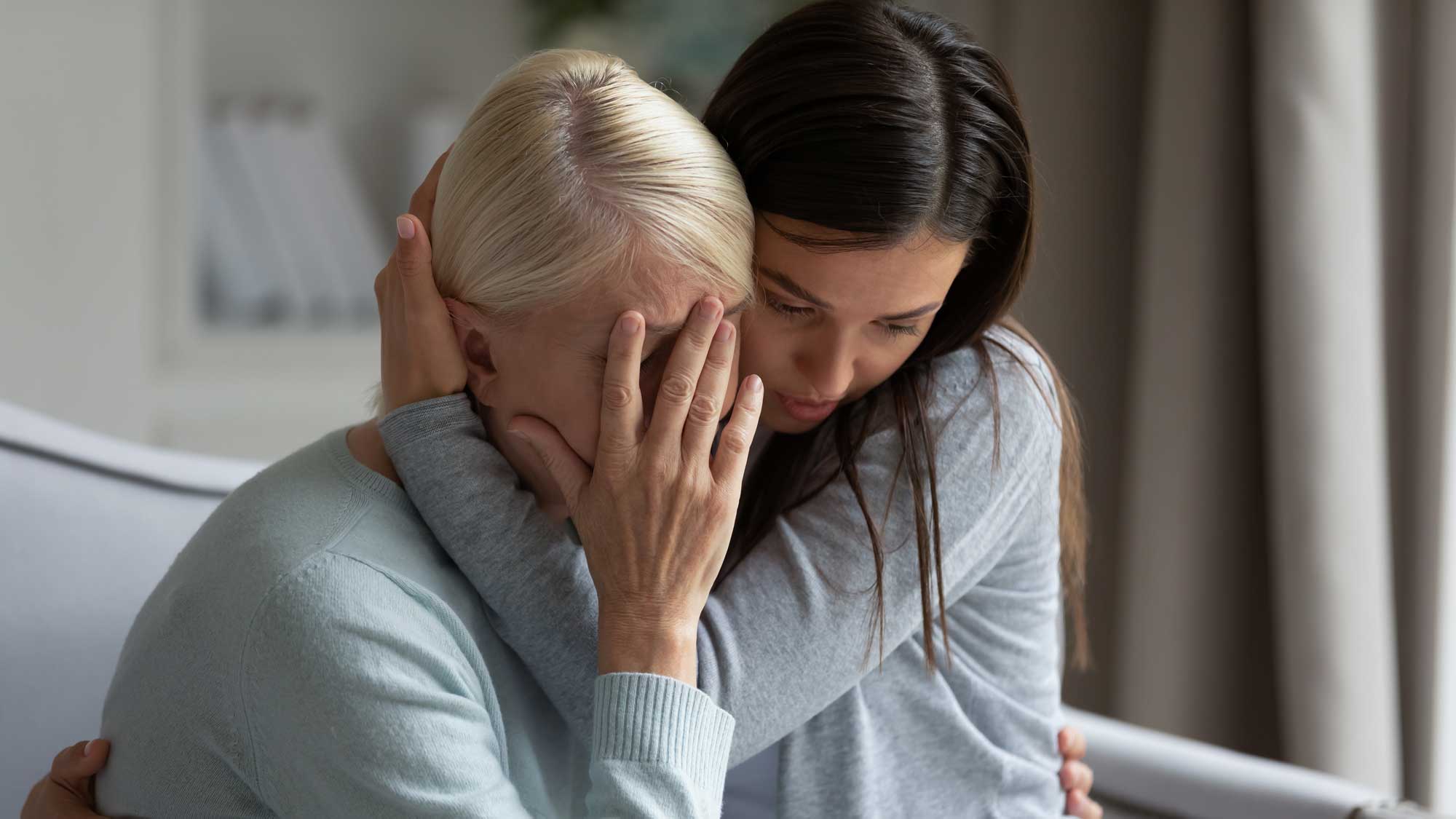 Woman with daughter crying over the loss of a loved one