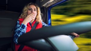 Woman yawning while driving a big rig truck